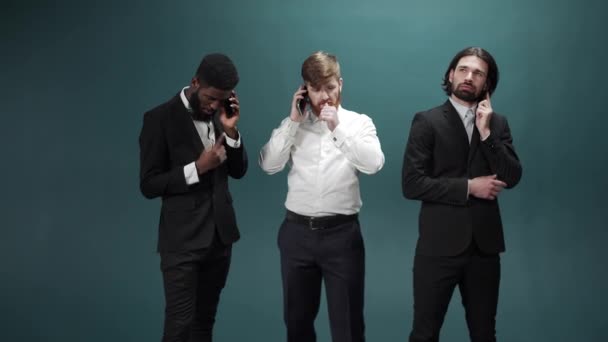 Drie mannen in smoking staan bij elkaar en praten in slow motion met de telefoon. — Stockvideo