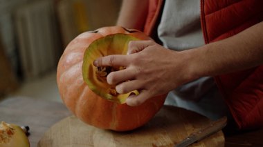 Kırmızı yelekli genç bir adam cadılar bayramı balkabağına dönüşüyor. 