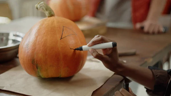 Mladá dáma kreslí oči a ústa na halloweenské dýni — Stock fotografie
