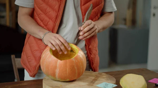 Un hombre talla una calabaza cuidadosamente — Foto de Stock