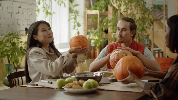 Amigos están sentados en la mesa y hablando de sus calabazas de halloween — Foto de Stock