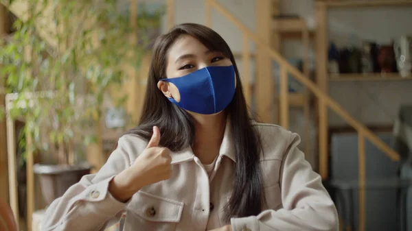 Eine junge Frau mit Gesichtsschutzmaske blickt in die Kamera — Stockfoto