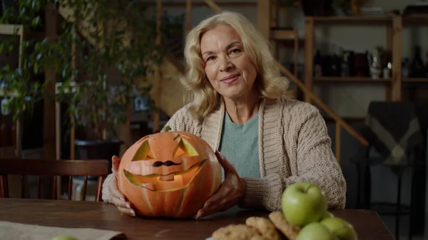 Una anciana sostiene una calabaza y mira a la cámara — Foto de Stock