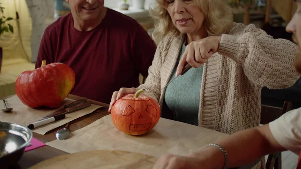 Starsza pani uczy się rzeźbić dynię na Halloween z rodziną. Obraz Stockowy