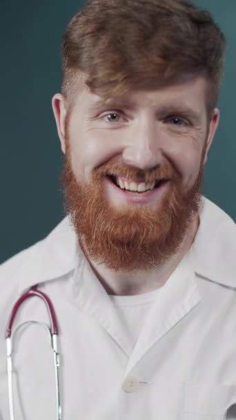 Giovane medico che indossa stetoscopio e cappotto medico su sfondo verde scioccato e ridendo, viso eccitato — Video Stock