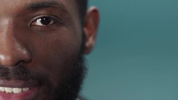 Młody czarny brodaty mężczyzna w oficjalnym garniturze mruga i patrzy w kamerę — Wideo stockowe