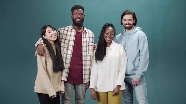 A group of four young guys of different nationalities happily hugging — Stock Video