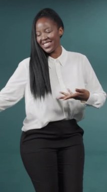 Yeşil arka planda ilham verici yüz ifadesiyle dans eden güzel siyah kadın.