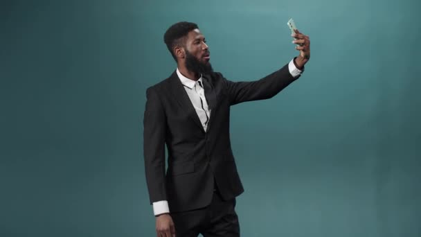 Гарненький африканський чоловік з темною бородою в білій сорочці і чорний костюм робить кілька фотографій на своєму телефоні — стокове відео