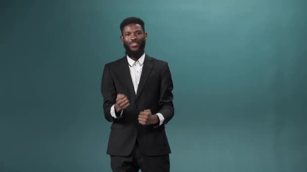 Egy afrikai vonzó férfi fekete szmokingban áll és örül az elért eseménynek. — Stock videók