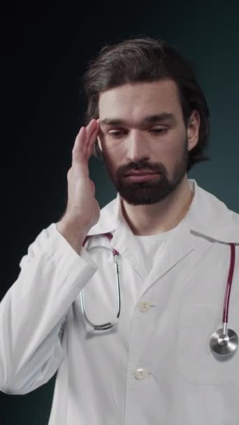 흰 코트를 입고 목에 청진기를 두르고 있는 젊은 의사는 두통약 한 두 통을 느낀다 — 비디오