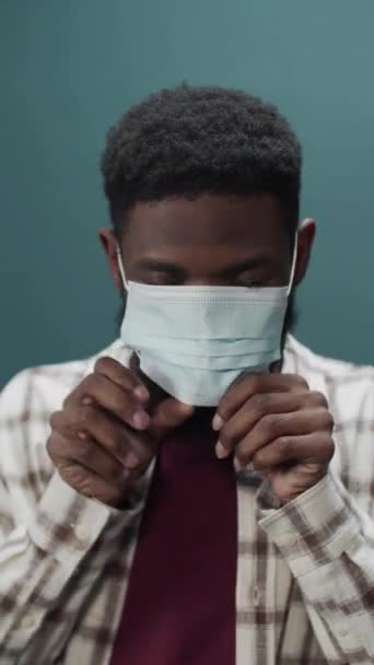 Привлекательный веселый черный парень надевает медицинскую защитную маску для защиты здоровья и профилактики во время вспышки вируса, эпидемии и инфекционных заболеваний — стоковое видео