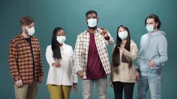 Un grupo interracial está mostrando una ampolla con la vacuna contra el coronavirus y haciendo un signo de pulgar hacia arriba — Vídeos de Stock