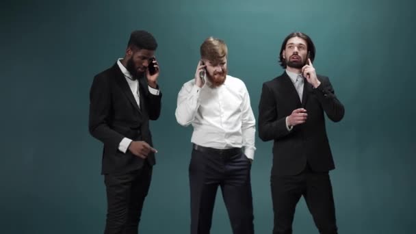 Drie mannen in smoking staan bij elkaar en praten met de telefoon. — Stockvideo