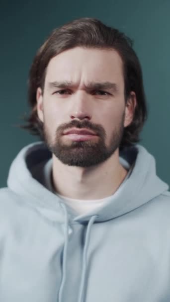 Isolated Dark-haired guy confused feels doubt while makes choice, dressed in casual hoodie — Stock Video