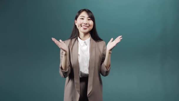 Een Aziatische aantrekkelijke vrouw in een formeel pak staat en applaudisseert terwijl ze naar de camera kijkt. — Stockvideo