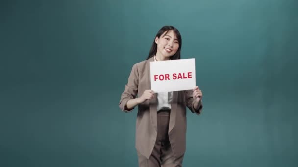 Une jeune femme asiatique en costume formel montre une affiche nommée à vendre — Video