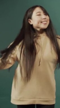 Uzun siyah saçlı komik pozitif kız yalnız dans ediyor, favori müziğe geçiyor, boş zamanların tadını çıkarıyor.