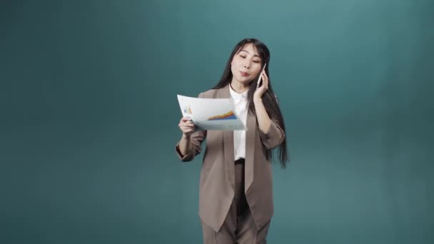 Ein Managermädchen in beiger Jacke und weißem Hemd mit Papieren in der Hand telefoniert — Stockvideo