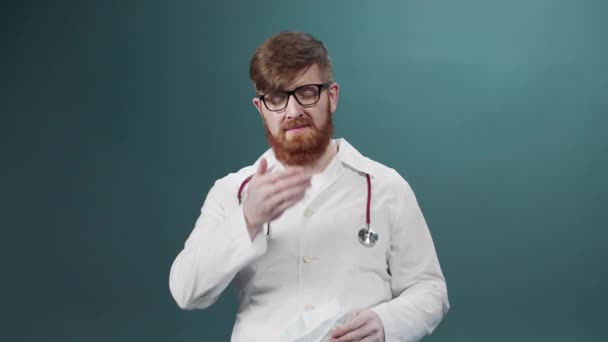 Een jonge aantrekkelijke dokter doet zijn masker af, gooit het weg en laat zien dat hij daar blij mee is. — Stockvideo