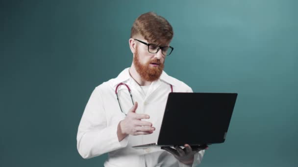 Genç kızıl sakallı bir doktor hastasıyla internetten video görüşmesi yapıyor. — Stok video