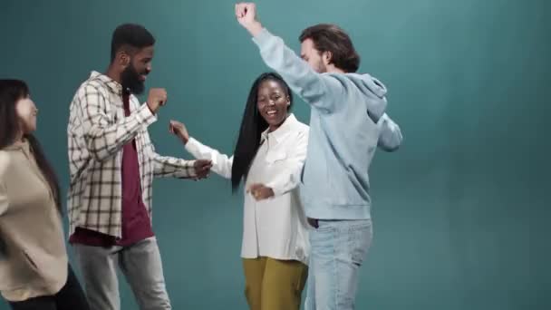 Amigos se están divirtiendo y bailando juntos en ropa casual sobre el fondo verde — Vídeos de Stock