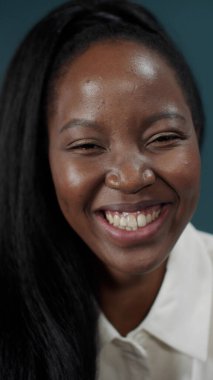 Uzun saçlı, koruyucu yüz maskesi takan, gülümseyen ve dans eden koyu tenli bir kız.