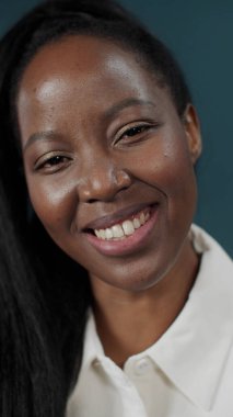 Güzel, genç bir kadın, yeşil duvar arkasında yalnız ve geniş bir gülümseme içinde poz veriyor.