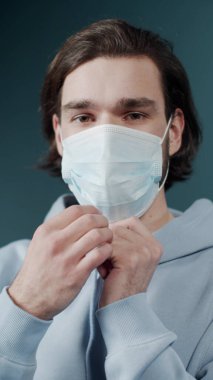 Açık renk kapüşonlu yakışıklı adam koruyucu yüz maskesi takıyor.