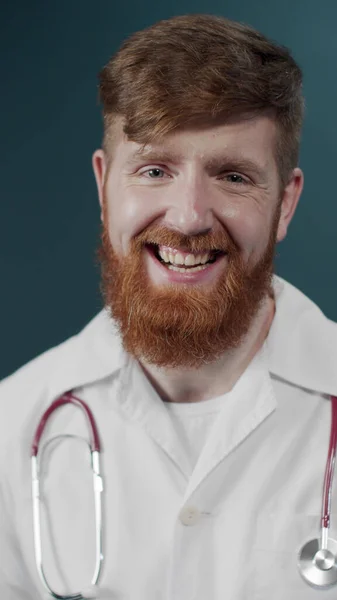 Young doctor man wearing stethoscope and medical coat over green background shocked and laughing, excited face — Stock Photo, Image