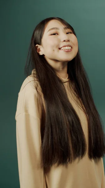 Atractiva chica china alegre con el pelo largo posando para la cámara, sonriendo y agitando las manos —  Fotos de Stock