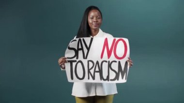 Güzel bir Afrikalı kız gururla ırkçılığa karşı bir poster gösteriyor ve uzaklaşıyor.