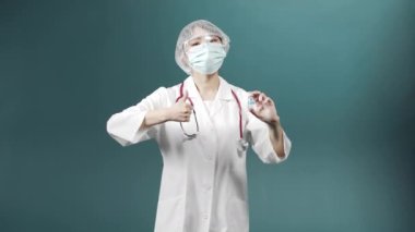 Beyaz üniformalı çekici bir Asyalı genç doktor kameraya bakıyor ve Coronavirus 'a karşı aşısı olan bir ampul gösteriyor.