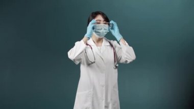 Sağlık üniformalı yorgun bir kadın özel bir ekipmanı çıkartıyor ve alnını ovuyor.