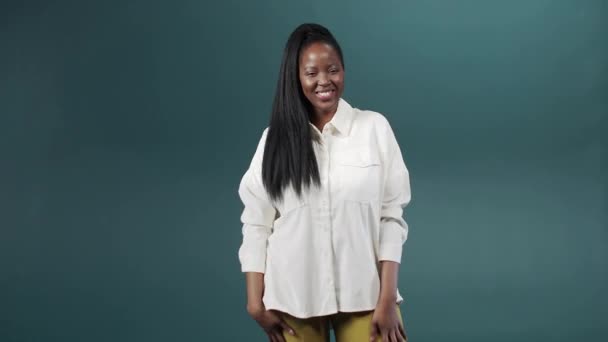 Een mooie jonge zwarte vrouw komt binnen en begint te poseren lachend naar de camera — Stockvideo