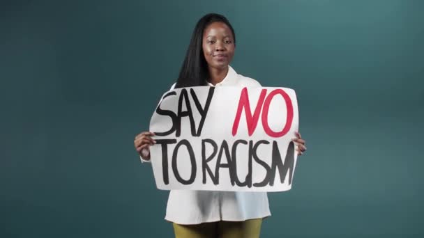 アフリカの美しい少女は人種差別に反対するポスターを誇らしげに見せ、歩き回っています — ストック動画