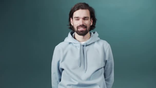 Un homme barbu timide se tient debout, réparant ses cheveux et regardant la caméra — Video