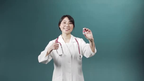 Привлекательный молодой врач улыбается и показывает ампулу с вакциной — стоковое видео