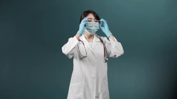 En trött upprörd kvinna i medicinsk uniform sätter av en speciell utrustning och gnuggar pannan — Stockvideo