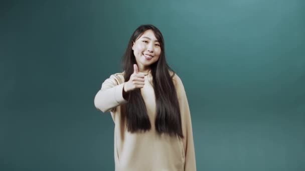 Egy vidám ázsiai nő felemeli a hüvelykujját és mosolyog. — Stock videók