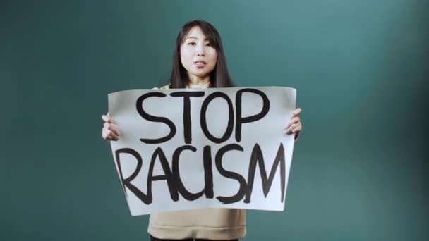 Красивая серьезная азиатка стоит и призывает всех бороться с расизмом. — стоковое видео