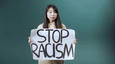 Ciddi bir Asyalı kadın ırkçılığa karşı bir afiş kaldırıyor.