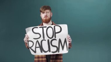 Kahverengi gömlekli çekici bir adam ırkçılığa karşı bir poster gösteriyor. 