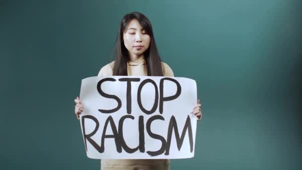 Μια σοβαρή Ασιάτισσα υψώνει αφίσα κατά του ρατσισμού. — Αρχείο Βίντεο