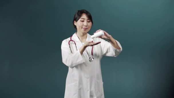 Kobieta w białej sukni medycznej dezynfekuje ręce i patrzy w kamerę. — Wideo stockowe