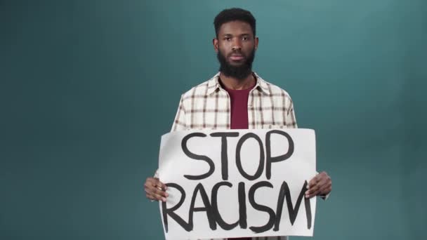 一个有魅力的黑人站在那里展示反对种族主义的海报 — 图库视频影像