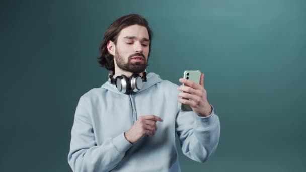 Un joven atractivo está de pie y haciendo un video en su teléfono inteligente — Vídeos de Stock