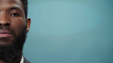 Genç Afrikalı sakallı bir adam kameraya ciddiyetle bakıyor. 