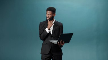 Güzel, koyu tenli sakallı bir adam elinde bir dizüstü bilgisayar tutuyor ve internette arama yapıyor.