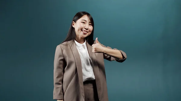 Uma mulher asiática alegre está mostrando um polegar para cima e sorrindo — Fotografia de Stock